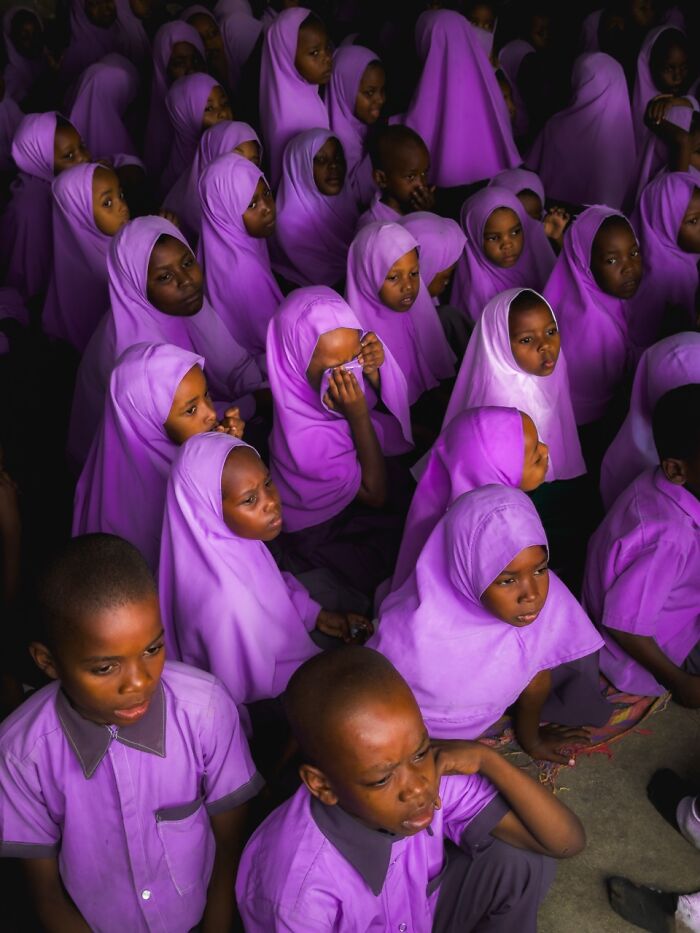 A high-angle shot captures numerous children wearing purple headscarves, part of the iPhone Photography Awards.