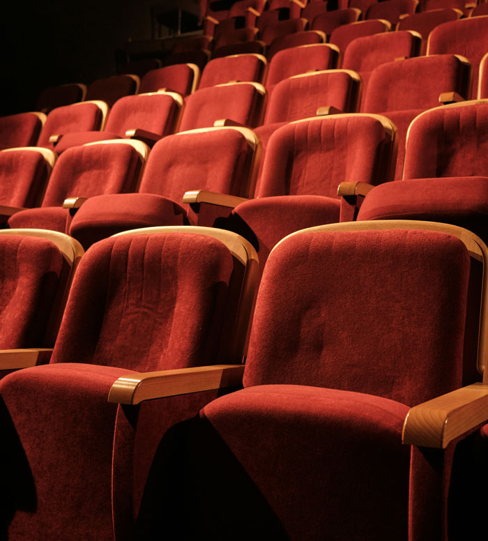 Rows of empty red velvet seats in a theater, representing surprisingly affordable entertainment options.