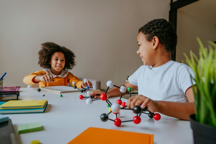 Two kids playing with molecular models, representing inquisitive minds and questions that leave parents stumped.