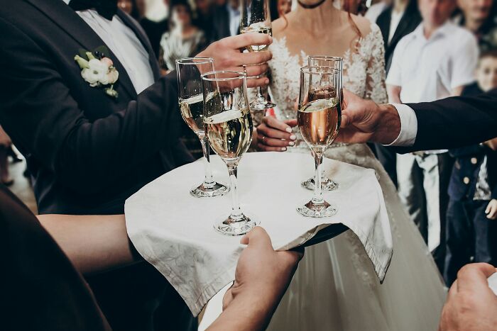 A newlywed couple toasting with champagne flutes at a wedding reception.