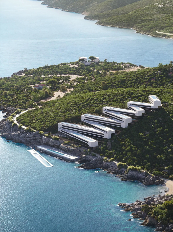 Modern architecture design: An aerial view of multiple contemporary buildings integrated into a lush green hillside overlooking a calm blue bay.