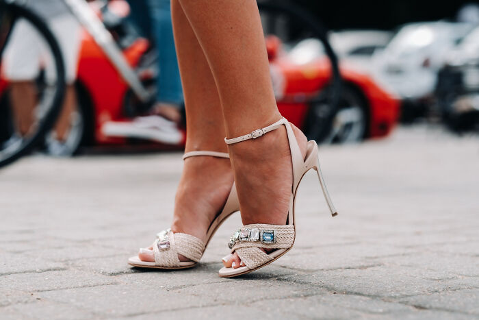 A close-up of a woman's feet in elegant high heels, highlighting products and fashion items.