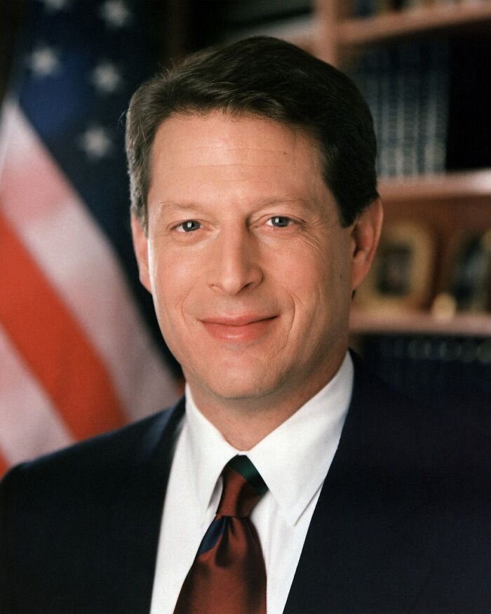 A headshot of Al Gore smiling, with an American flag in the background, relating to historical myths.
