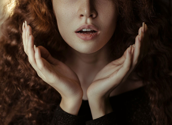 Close-up of a shocked woman with red, curly hair and hands cupped, reacting to her husband's decision to transition. Close-up of a shocked woman with red, curly hair and hands cupped, reacting to her husband's decision to transition.