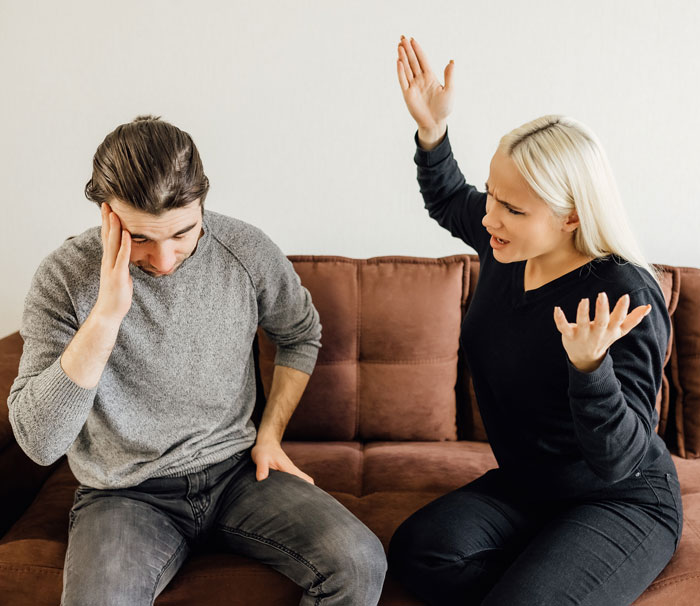 A man and a woman arguing on a sofa, depicting relationship stress after having a baby.
