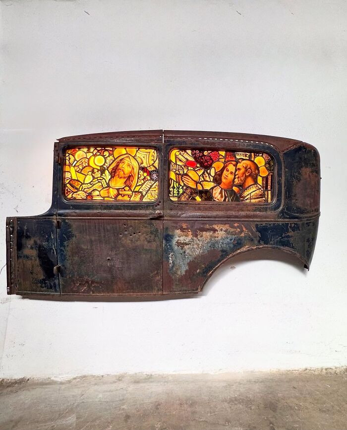 Side view of a burned and rusted Porsche 911 with extraordinary stained-glass sculpture windows.