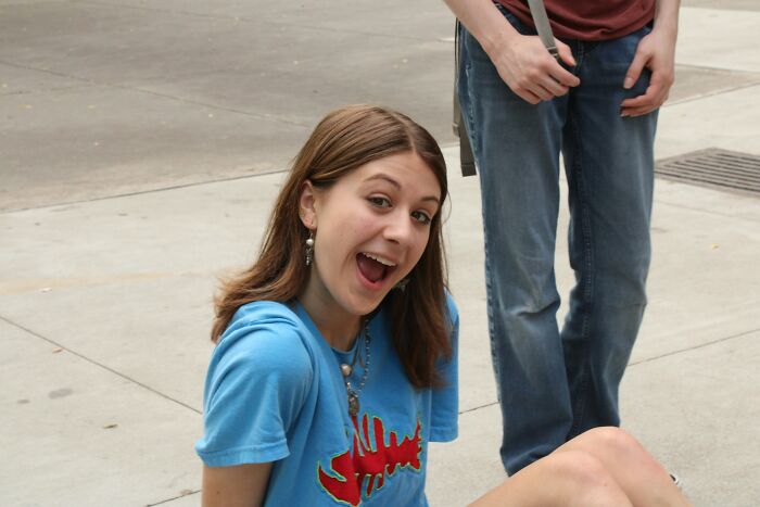 A young woman with an open mouth, sitting on the ground, representing discussions on age-gap relationships.