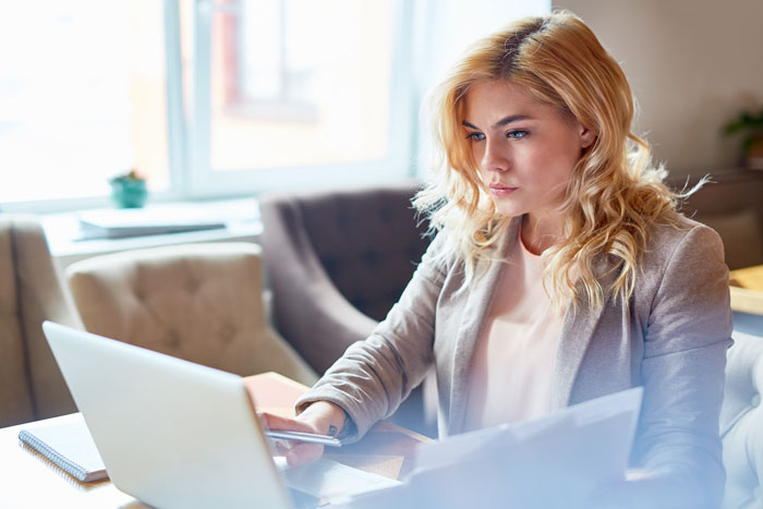 A woman working on a laptop, possibly researching divorce lawyer options for issues beyond cheating.