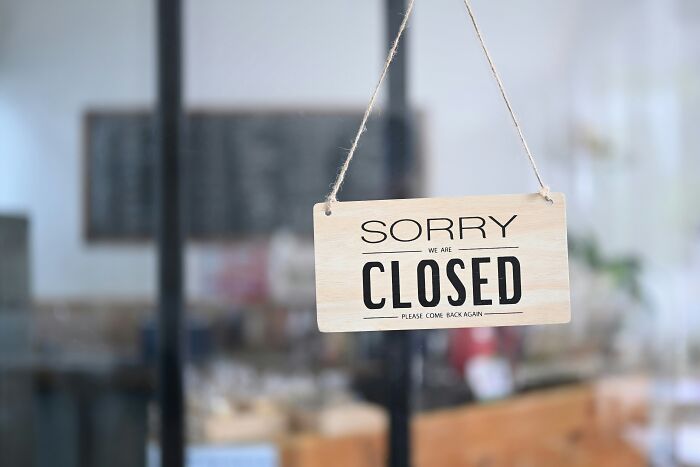 A Sorry We Are Closed sign hanging in a window, representing reasons why people got fired from their jobs.