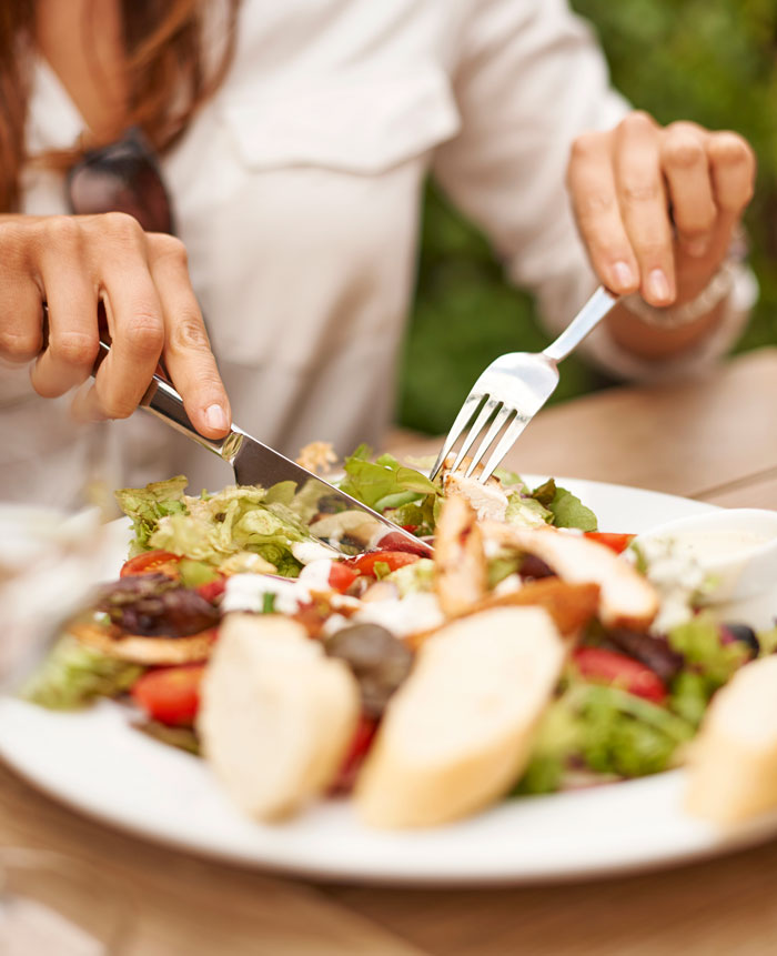 A person eating a salad with chicken and bread. This image can be used for boss stories that make you quit your job.