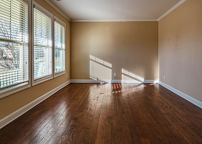 Empty room with wooden floors and sunlight streaming through blinds, highlighting reasons women leave a man's home.