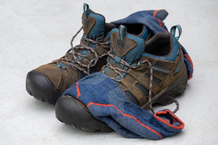 Dirty hiking boots with blue socks, representing unhygienic footwear.