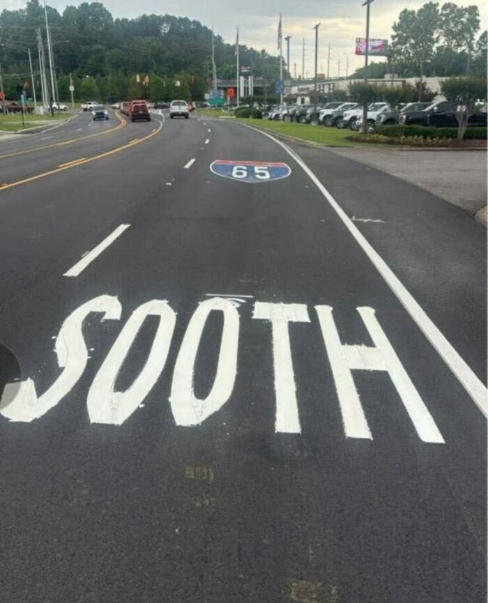 A road with the word SOOTH painted incorrectly instead of SOUTH, next to an interstate 65 sign. Example of cultural decline.