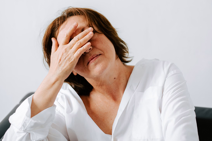 A woman covers her face with her hand, depicting exasperation from infuriating mansplaining examples.