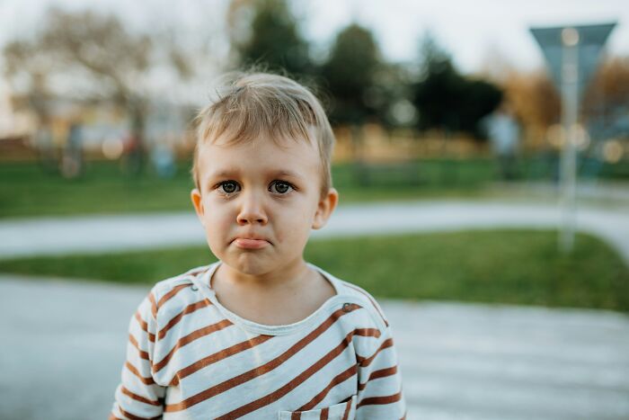 A young boy with a sad expression, reflecting parents stumped by the challenging questions kids ask.