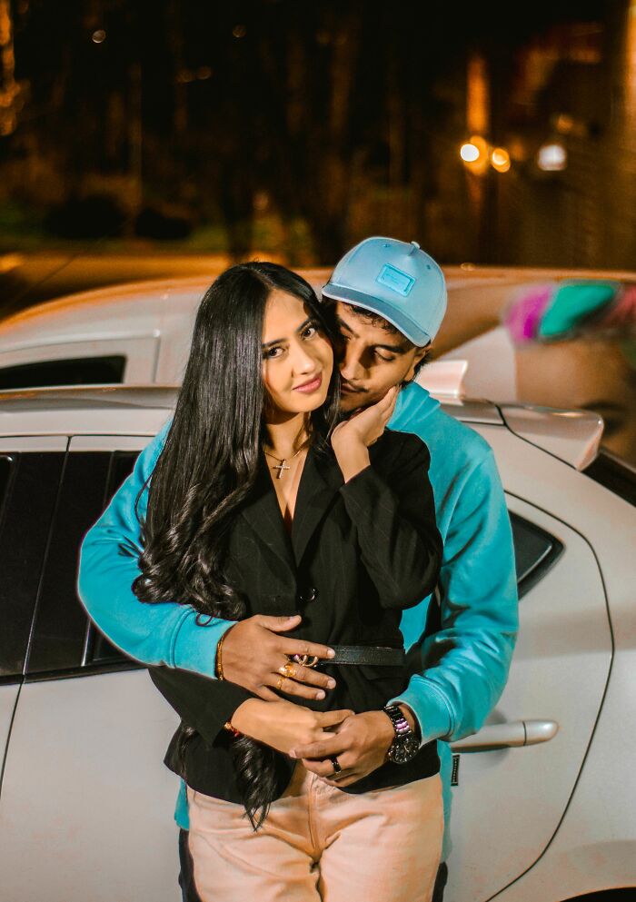 A young couple embracing at night next to a car, illustrating an age-gap relationship.