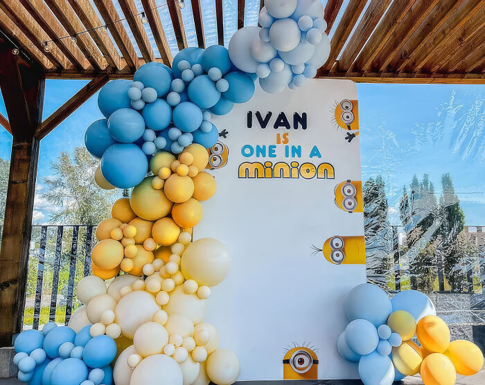 A Minions-themed balloon arch and backdrop for a birthday party, regretting money spent on this event.