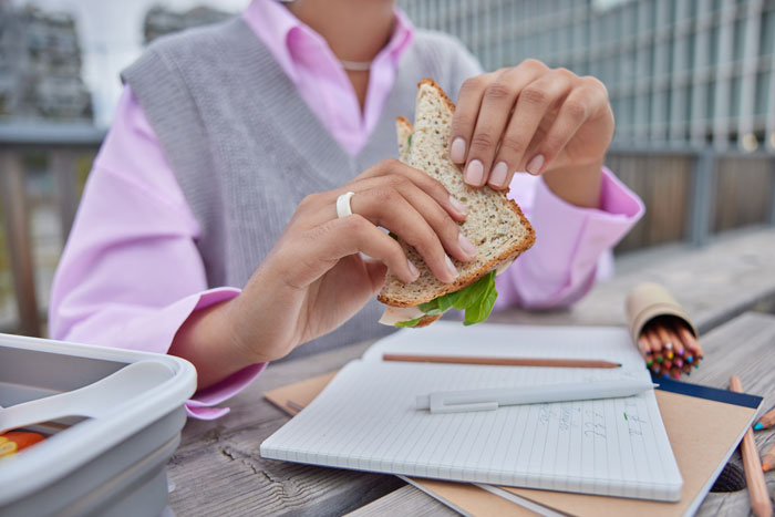 A person eating a sandwich at a picnic table with a notebook and colored pencils. This image can be used for boss stories that make you quit your job.