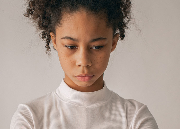 A young person looking down with a sad expression, feeling the loneliest time. Some people no longer look forward to their birthdays.