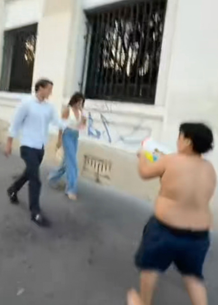 A 14-year-old boy aims a water toy at two adults on a street, accused of terrorizing tourists. A 14-year-old boy aims a water toy at two adults on a street, accused of terrorizing tourists.
