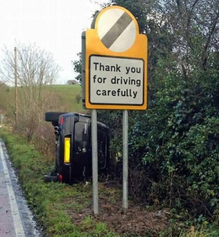 An overturned car next to a sign that says Thank you for driving carefully, highlighting cultural decline.