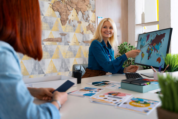 A travel agent points to a map on a computer, offering surprisingly affordable travel options for customers.