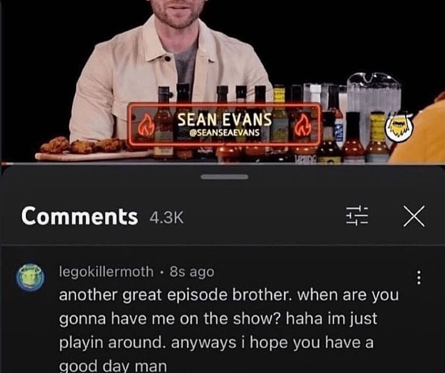 Screenshot of Sean Evans with Hot Ones sauces and a user comment asking to be on the show, a funny, unhinged screenshot.