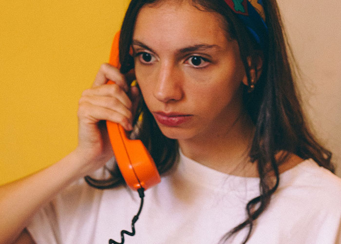 A young woman with an orange phone, reflecting on moments when reality break.