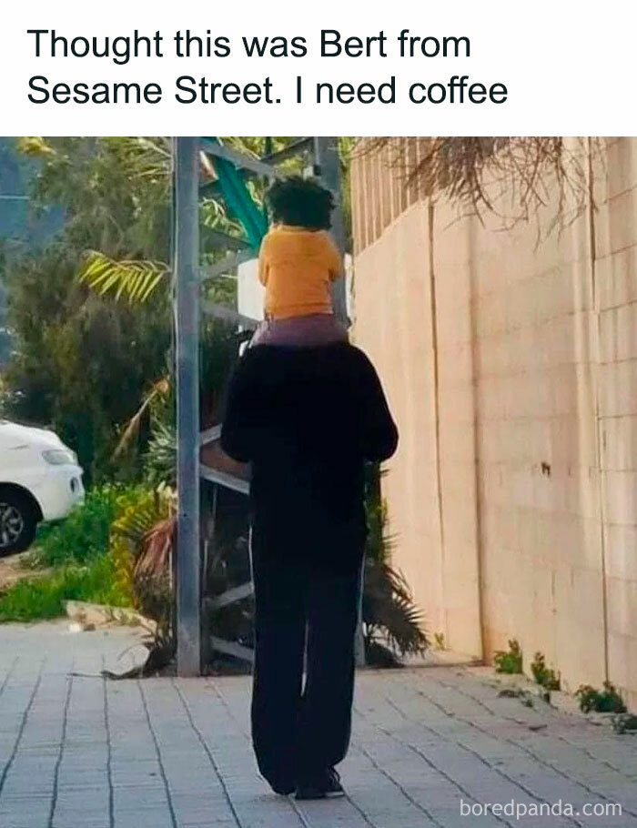 A person with a child on their shoulders, appearing to have a small head, a completely confusing photo.