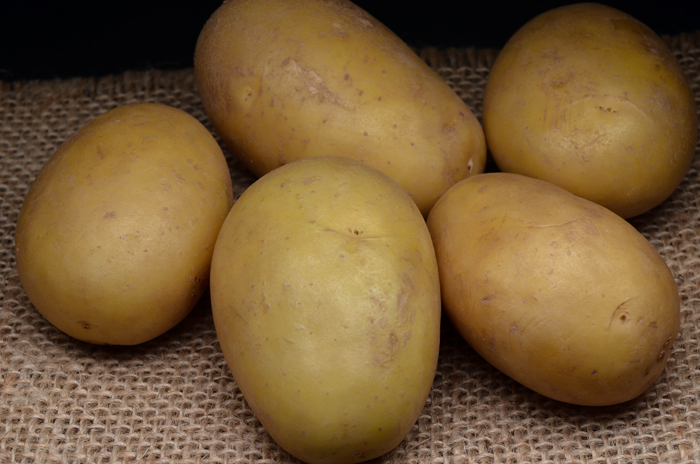 Five potatoes on a burlap surface, seemingly normal but related to creepy and mysterious things that happened to people.