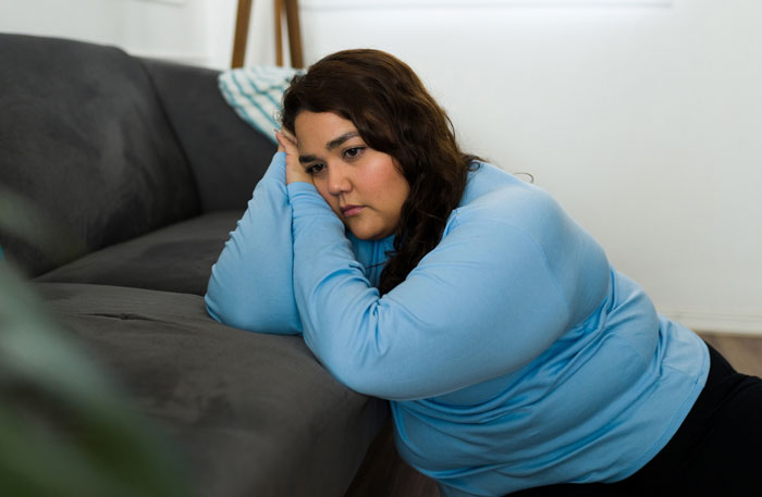A woman resting her head on a couch, looking sad. Women share hard truths about life.