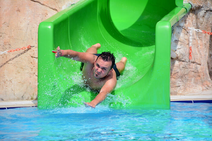 Man sliding down a green water slide; some of the dumbest reasons people got fired from jobs.