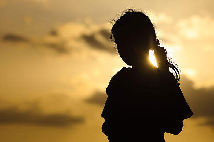 A silhouette of a child against a sunset, representing the impact of unfortunate names on kids.