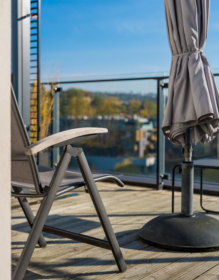An outdoor patio with a chair and closed umbrella, representing affordable luxuries people once thought were only for the rich.