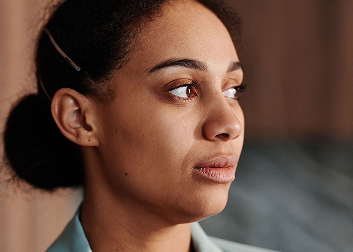 A woman looking thoughtfully to the side, reflecting on women's experiences visiting a man's home for the first time.
