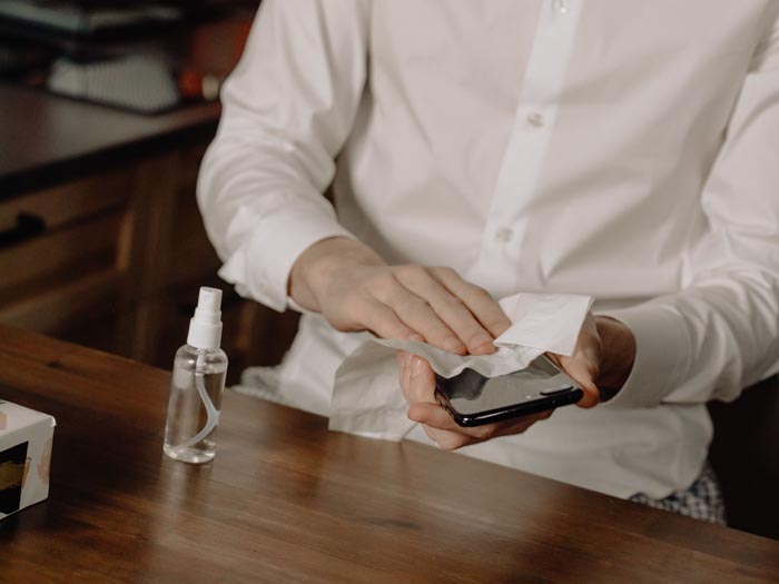 A man cleaning a phone, contrasting with unhygienic behaviors mentioned.