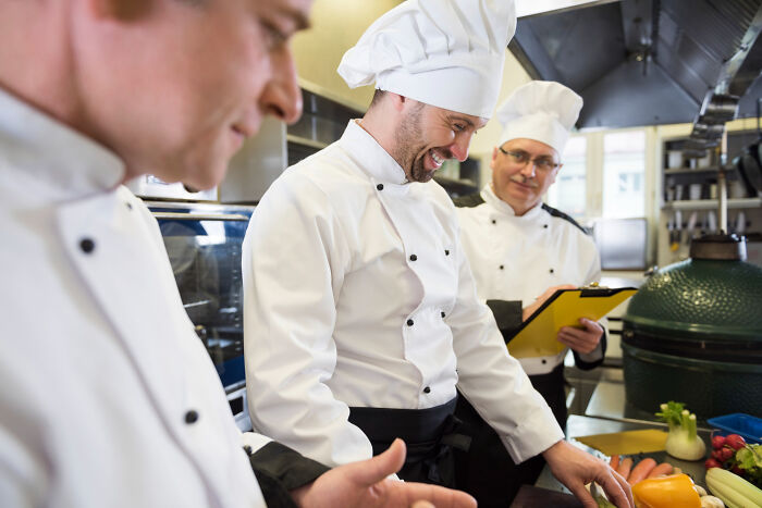 Three chefs working in a professional kitchen, demonstrating jobs that make women swipe left.