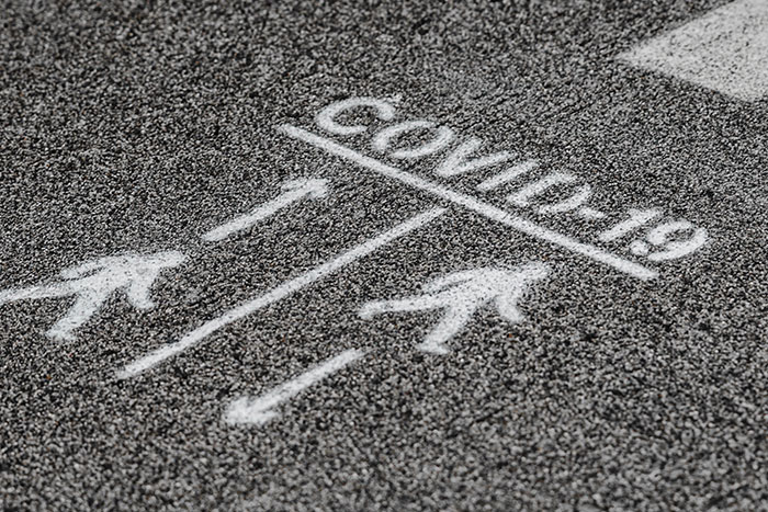 COVID-19 written on asphalt with arrows and figures, implying a difficult path for kids with unfortunate names.