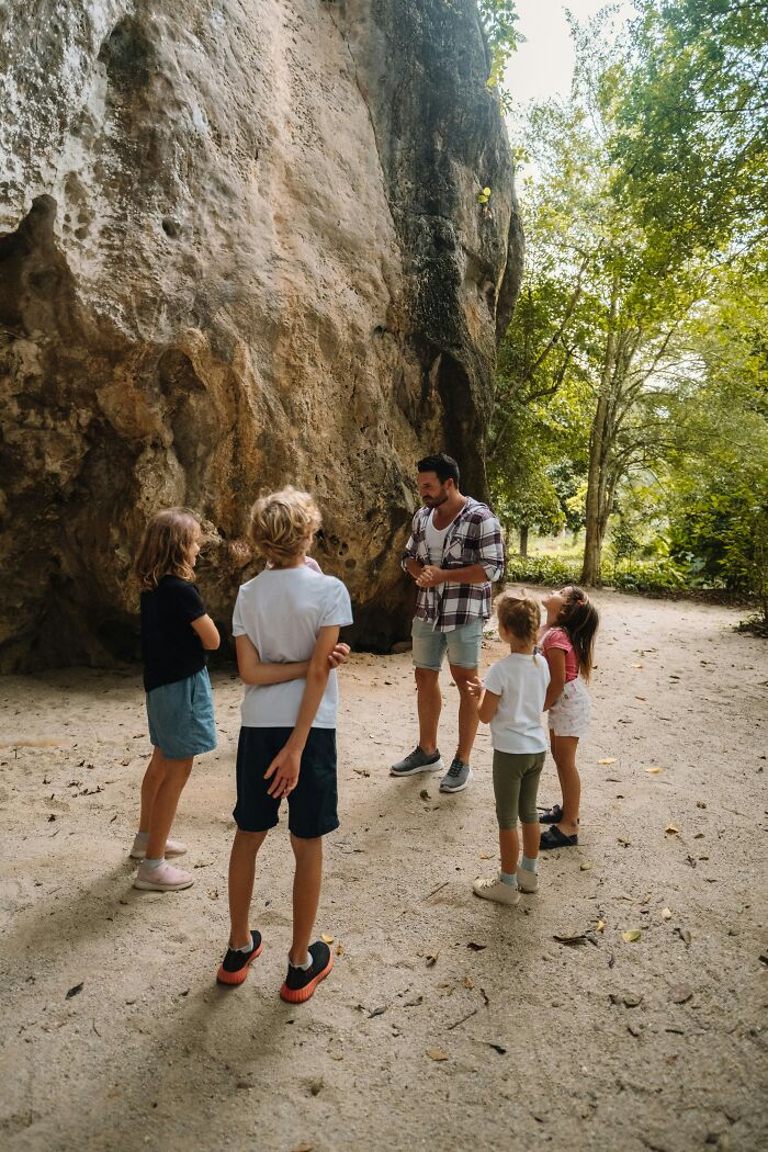 A parent and kids exploring a large rock formation outdoors, symbolizing the questions kids ask parents.