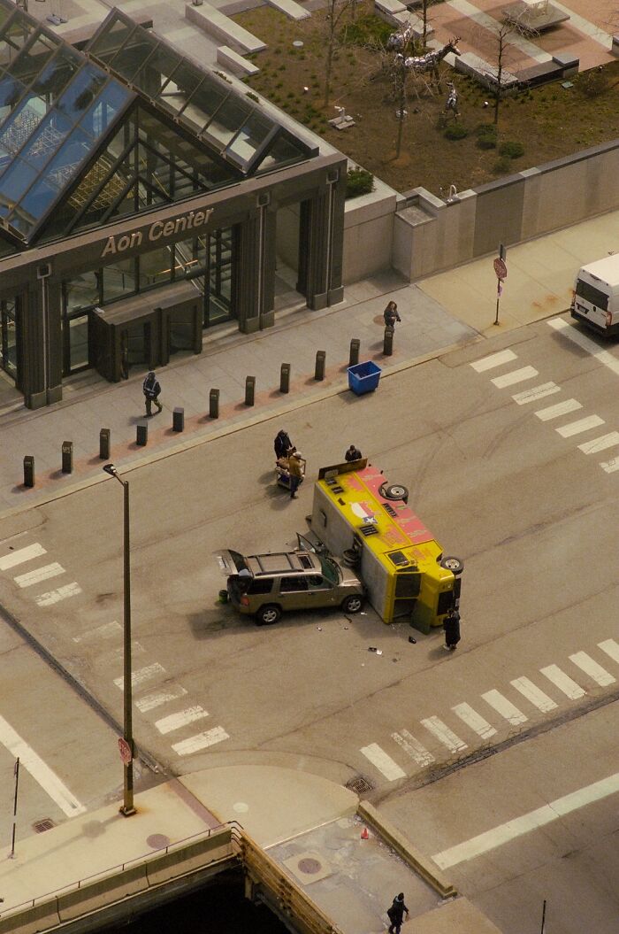 Dramatic color photo of an overturned yellow vehicle and a damaged car on a city street, capturing the world.