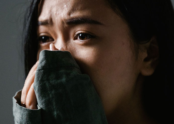 A woman covering her face, depicting women's experiences visiting a man's home for the first time.