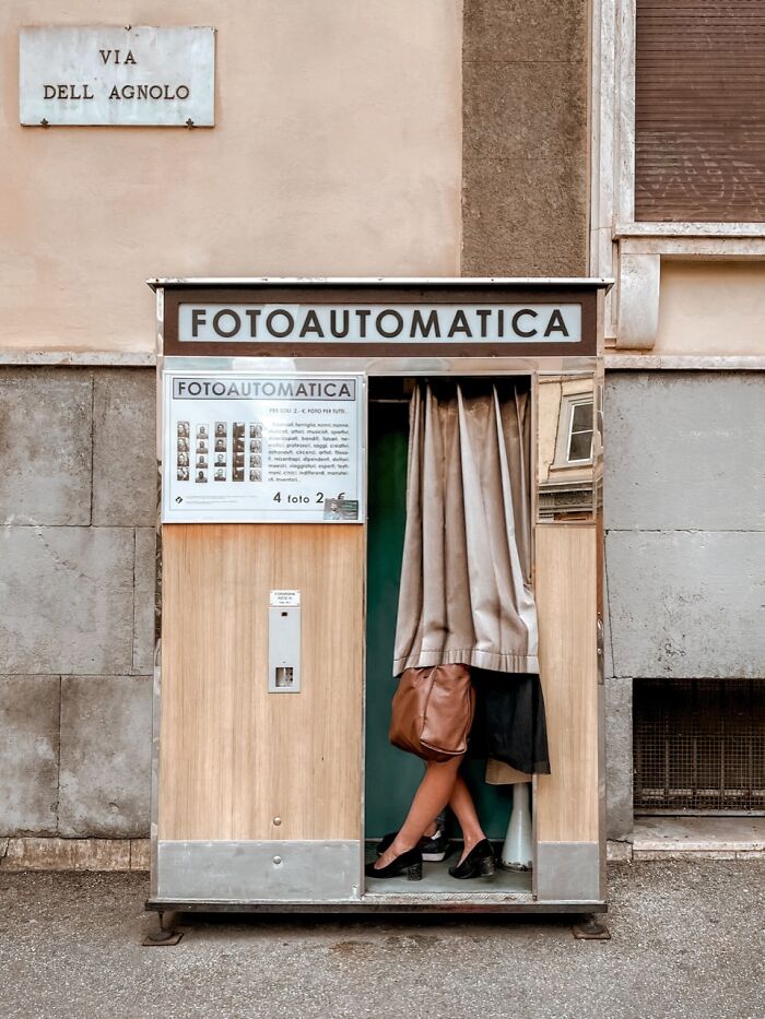 An artistic iPhone photography awards winning photo of a person entering a vintage Fotoautomatica booth on a city street.