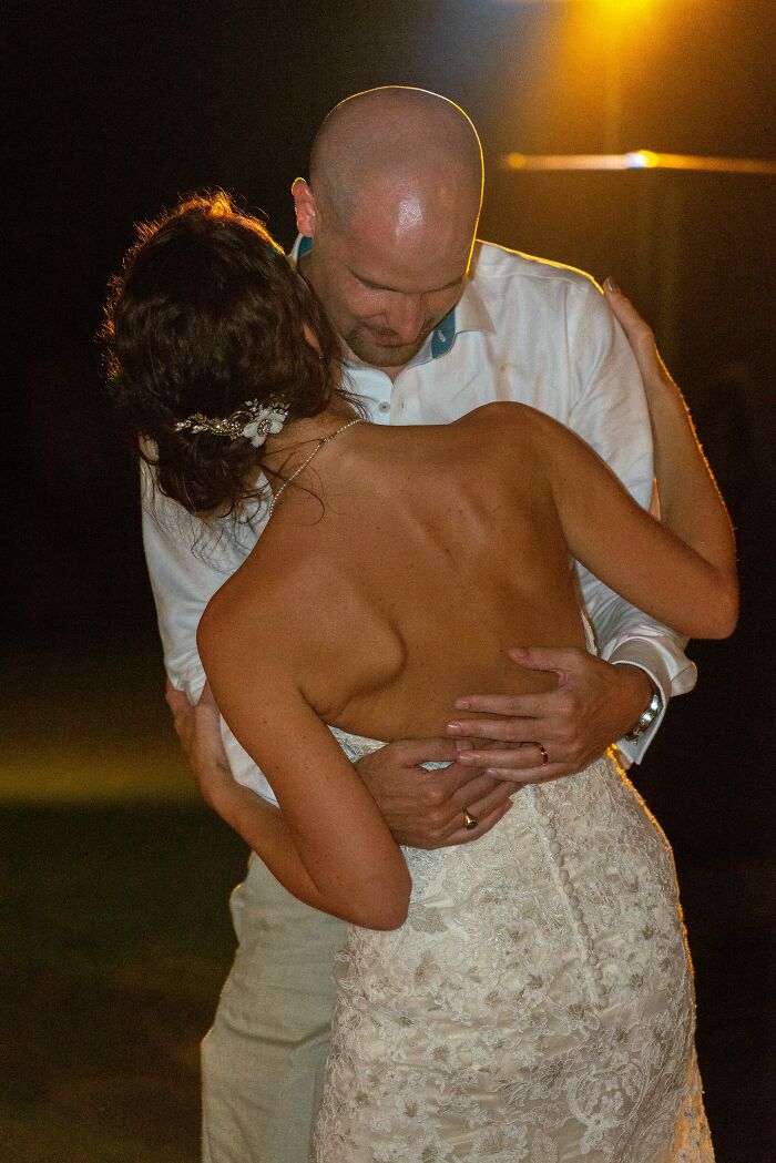 A couple slow dancing at their wedding, the groom embracing the bride with her back to the camera. An image related to wedding regrets.
