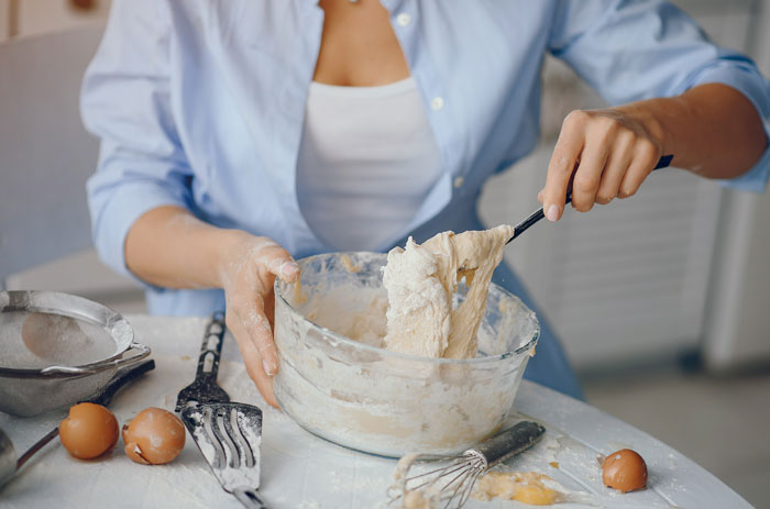 A woman baking, mixing dough in a bowl, sharing truths women learned.