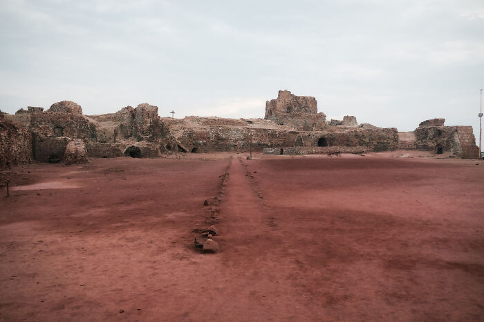 Ancient stone ruins in a red dirt landscape, an archaeological site within the Strait of Hormuz region.