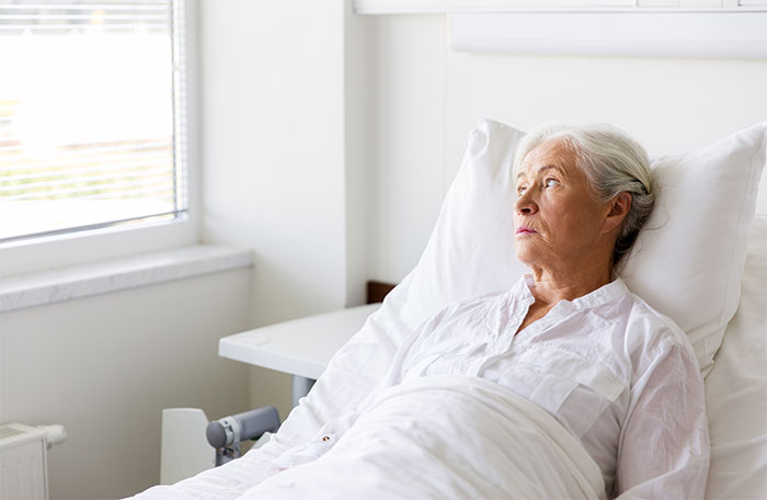 An elderly woman lies in a hospital bed, looking distraught after a crazy MIL's potion incident, showcasing the consequences.