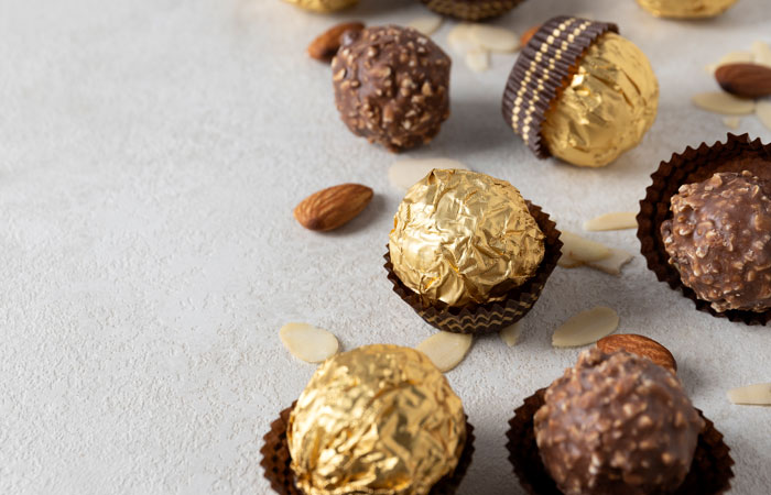 Assorted chocolates and almonds on a white surface, demonstrating how treats can be surprisingly affordable.