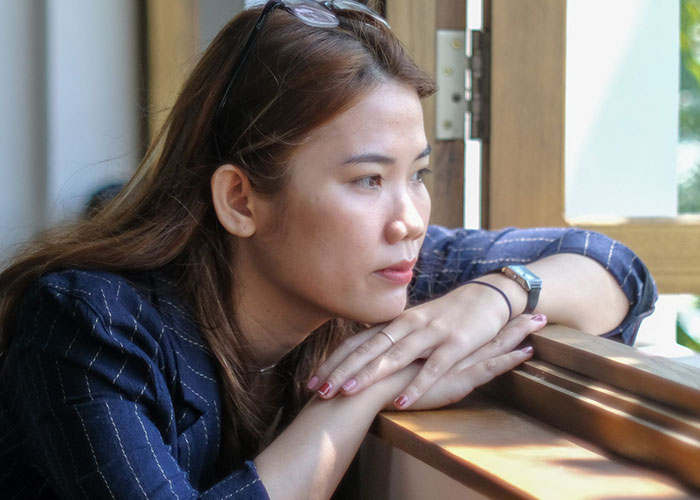A thoughtful person looking out a window, reflecting on the loneliest time and not looking forward to birthdays.