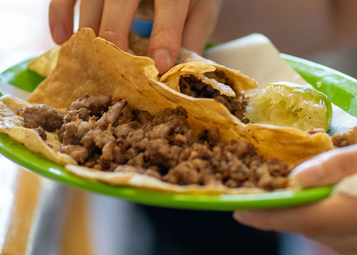 Hands holding a plate of tacos, representing the varied experiences of women at a man's home for the first time.