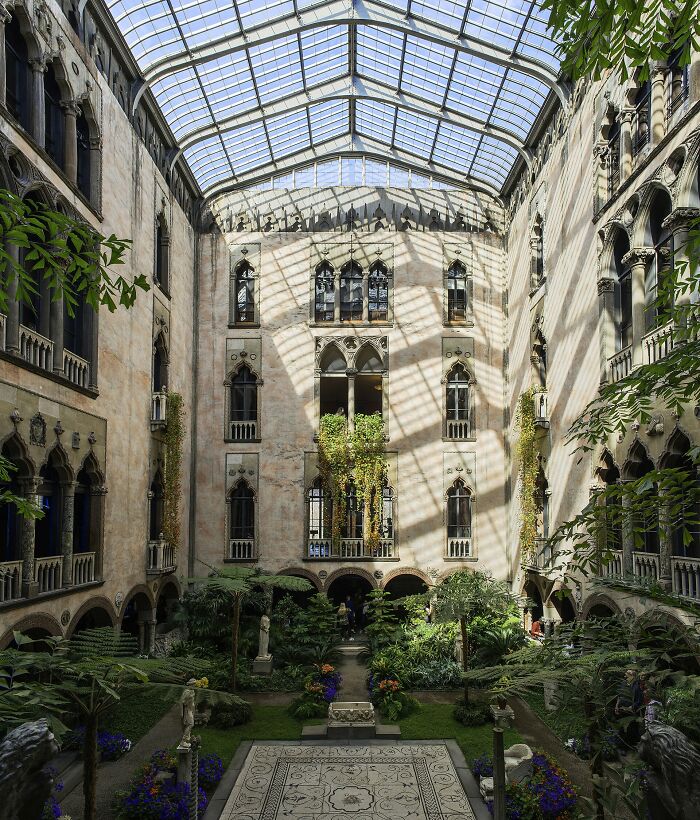 An ornate inner courtyard with lush greenery and a glass roof, hinting at unsolved mysteries within historic sites.